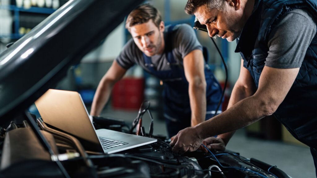 Two mechanics checking a regular car's engine maintenance